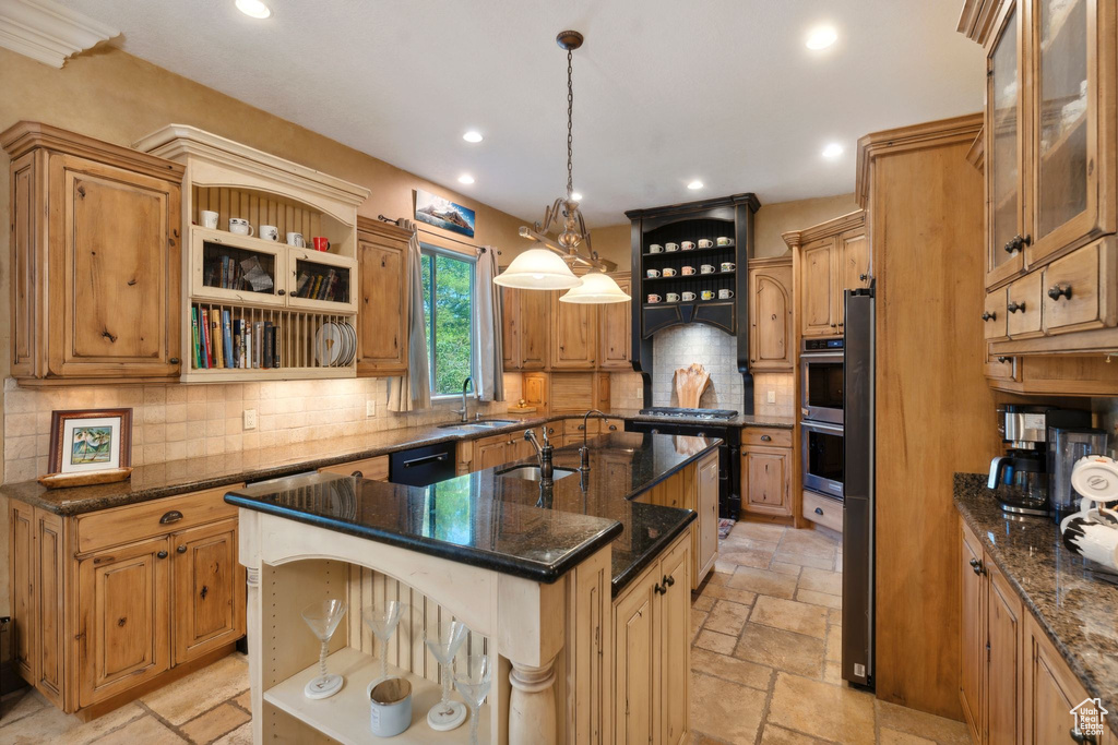 Kitchen featuring open shelves, a sink, stone tile flooring, a kitchen island with sink, and tasteful backsplash