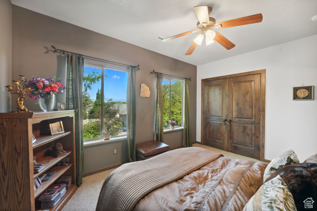 Bedroom with light carpet, multiple windows, baseboards, and ceiling fan