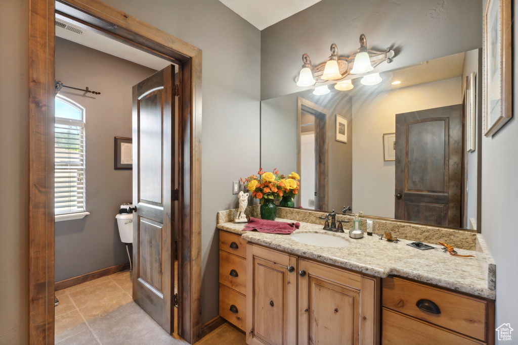 Bathroom with toilet, vanity, and tile patterned flooring