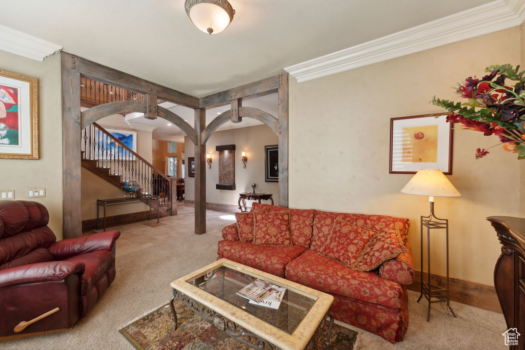 Carpeted living room with arched walkways, stairs, crown molding, and baseboards