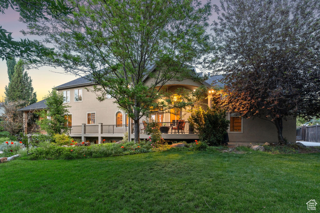 Rear view of house featuring stucco siding, a yard, and a deck