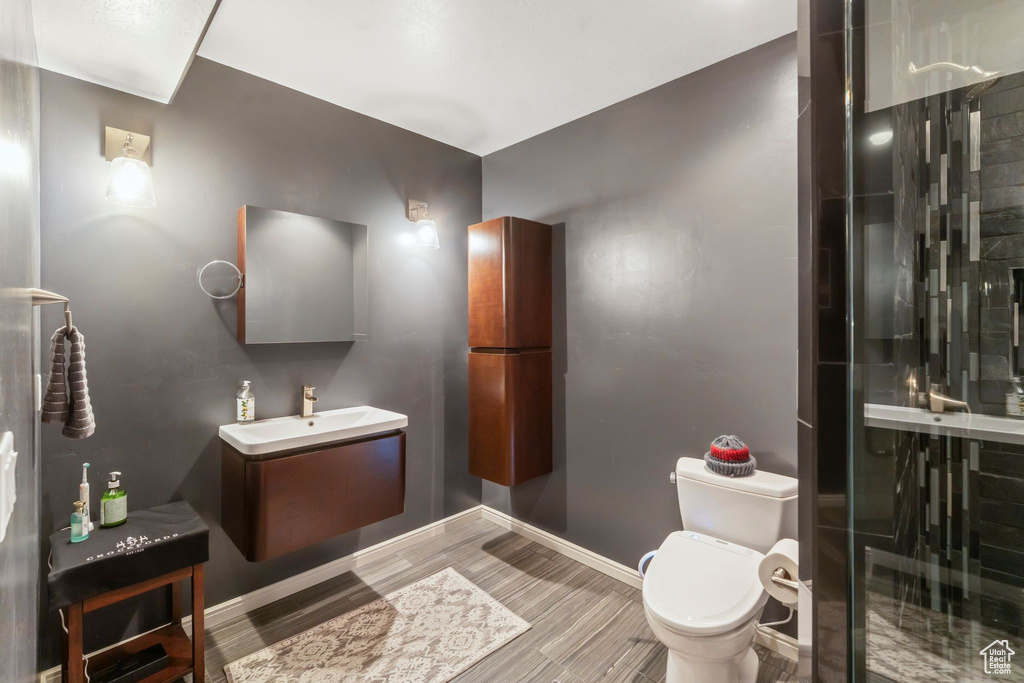Bathroom with vanity, toilet, a stall shower, baseboards, and wood finished floors