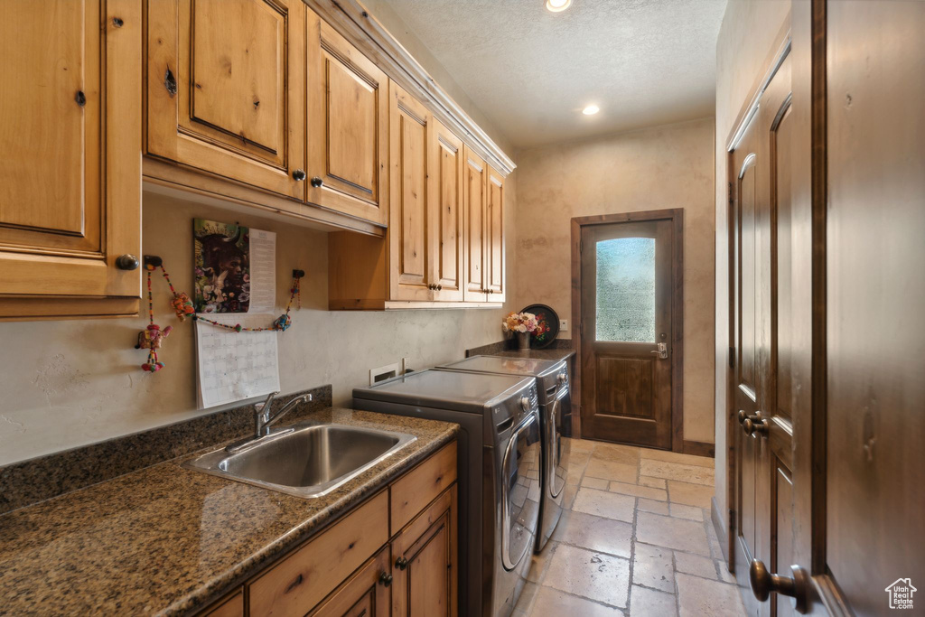 Laundry room featuring washing machine and dryer, cabinet space, stone tile floors, recessed lighting, and a textured ceiling