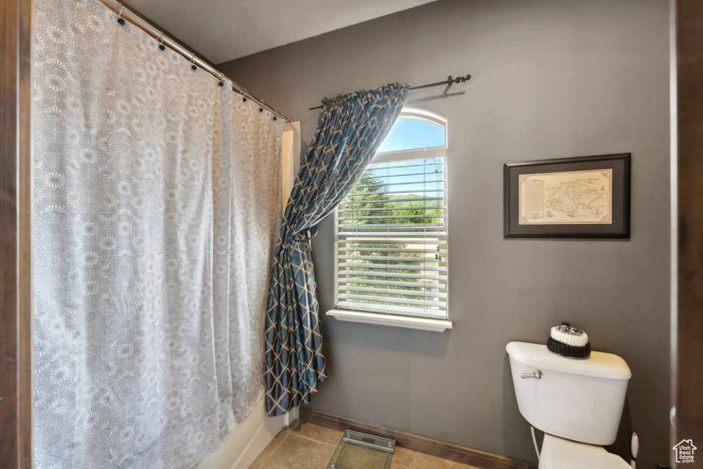 Full bath featuring toilet, baseboards, tile patterned flooring, and a shower with curtain