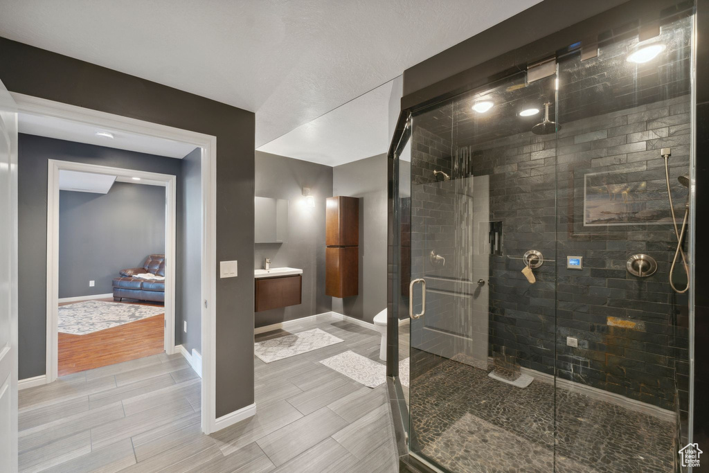 Full bath featuring a shower stall, wood finish floors, baseboards, and vanity