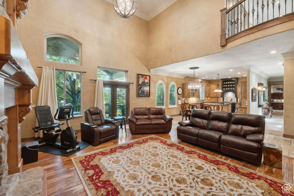 Living room featuring light wood finished floors, ornamental molding, a towering ceiling, and a chandelier