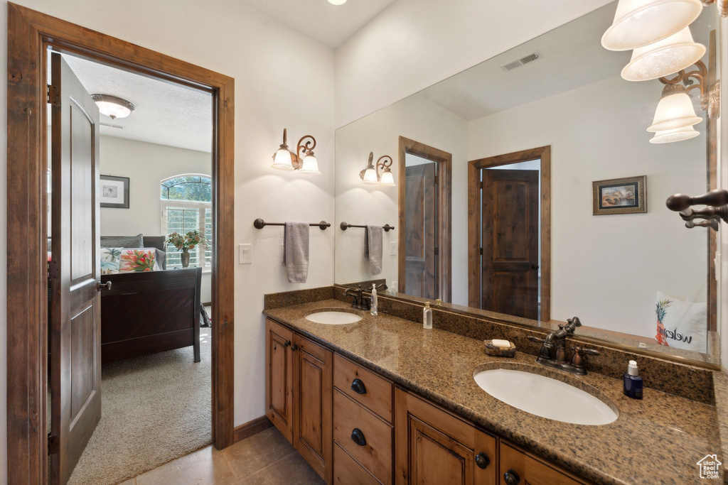 Full bath featuring double vanity, tile patterned floors, and baseboards