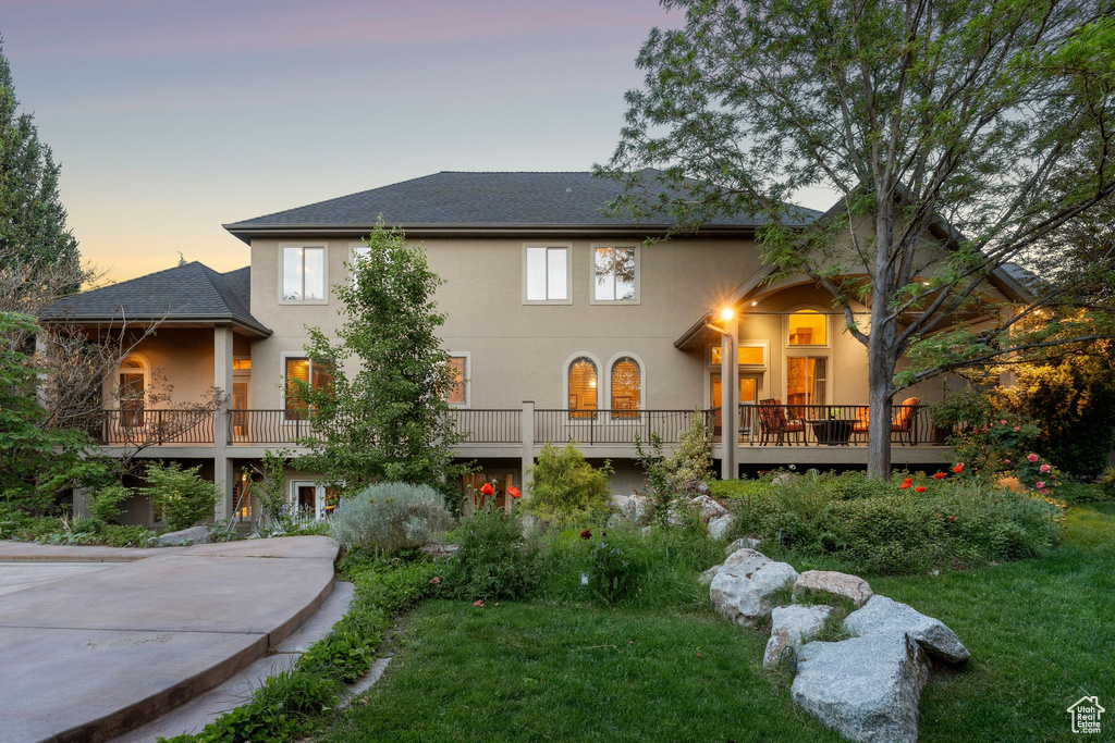 View of front of property with stucco siding, a yard, and roof with shingles