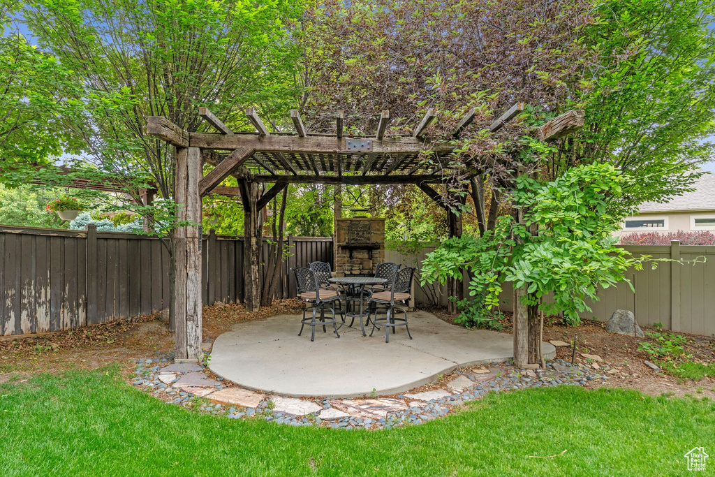 Fenced backyard with a patio, a pergola, and an outdoor stone fireplace