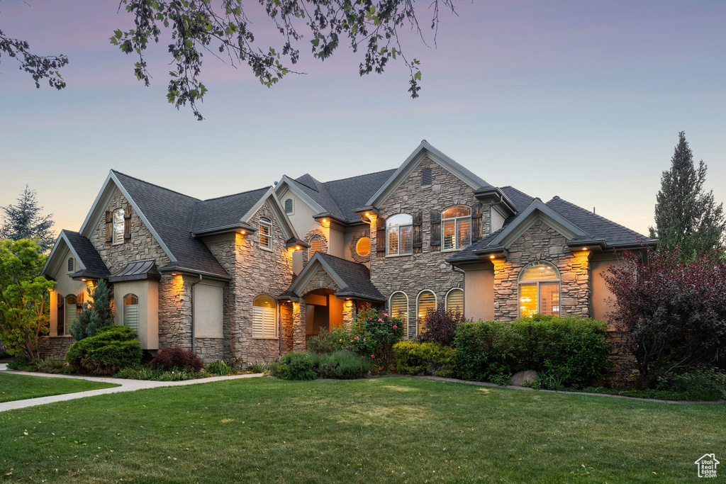 View of front of home featuring stone siding, a yard, and stucco siding