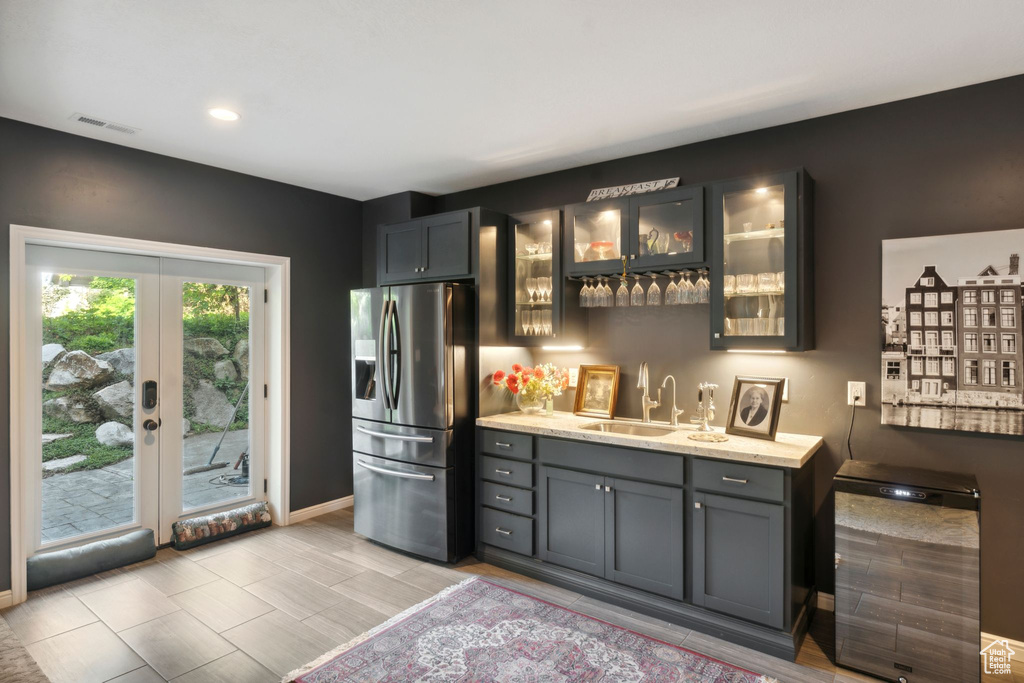 Indoor wet bar featuring stainless steel fridge, baseboards, french doors, and recessed lighting