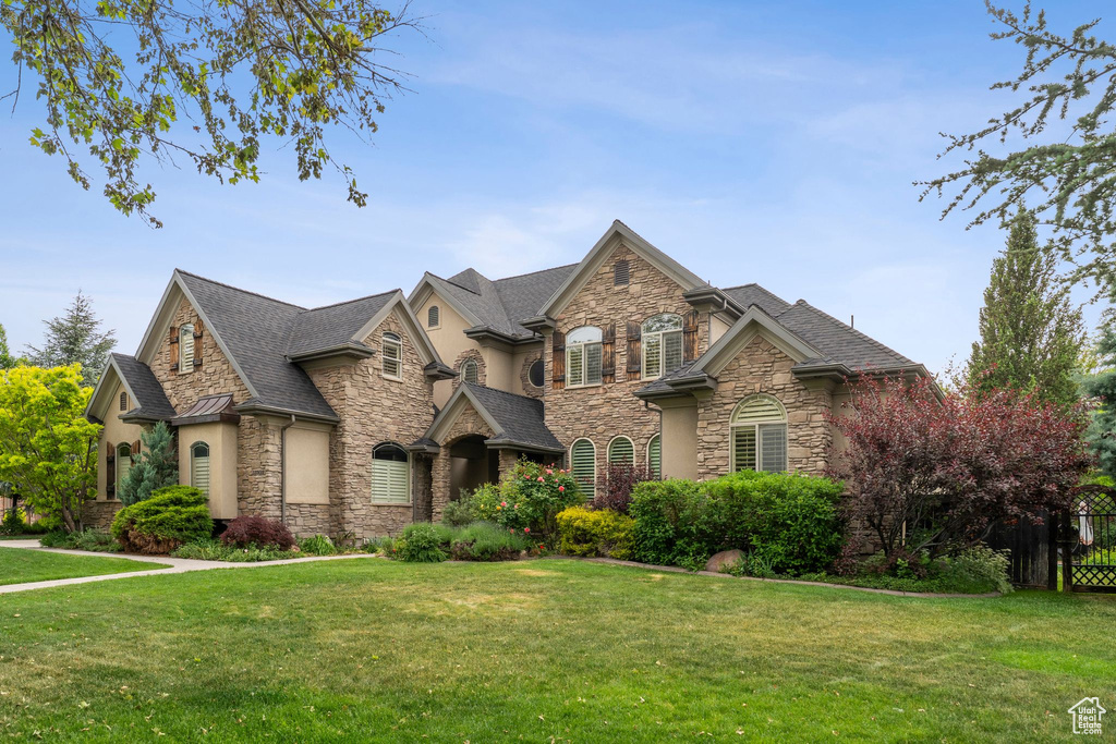 French provincial home with stone siding, a shingled roof, and stucco siding
