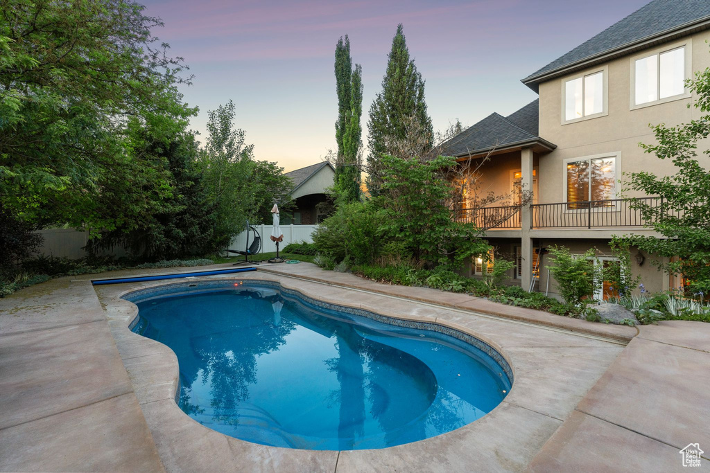 Pool at dusk featuring a fenced backyard and a patio area