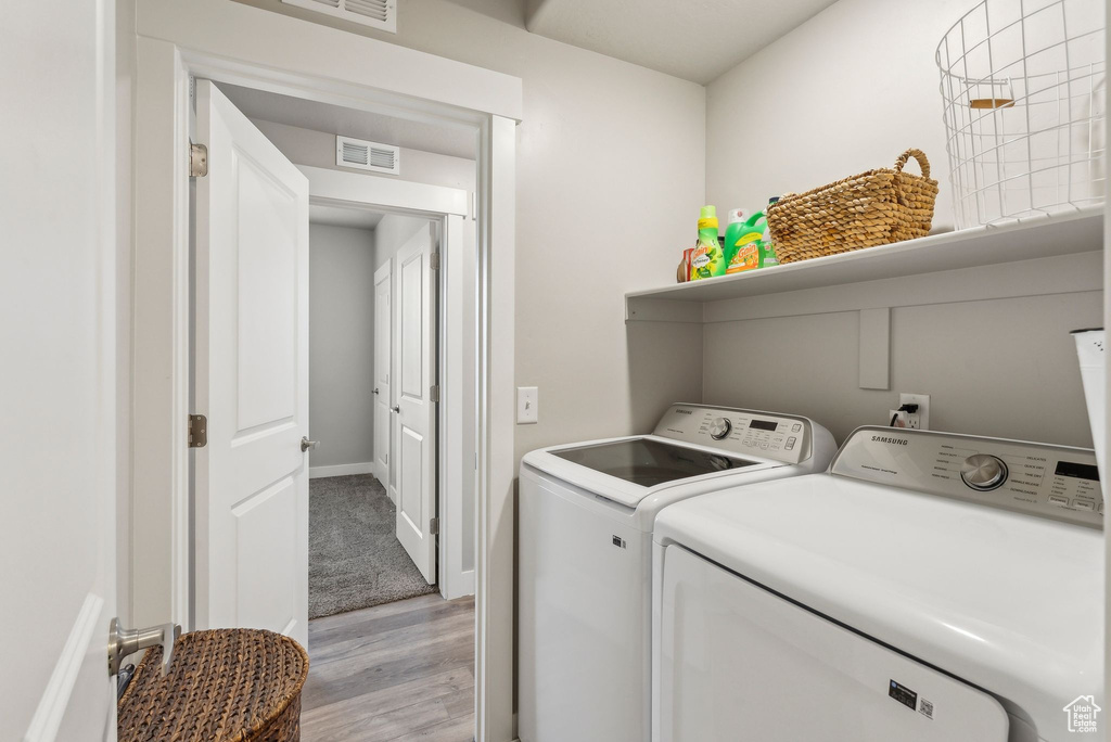 Laundry room featuring washer and dryer, light wood finished floors, and baseboards
