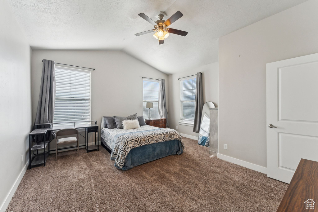 Carpeted bedroom with vaulted ceiling, baseboards, a ceiling fan, and a textured ceiling