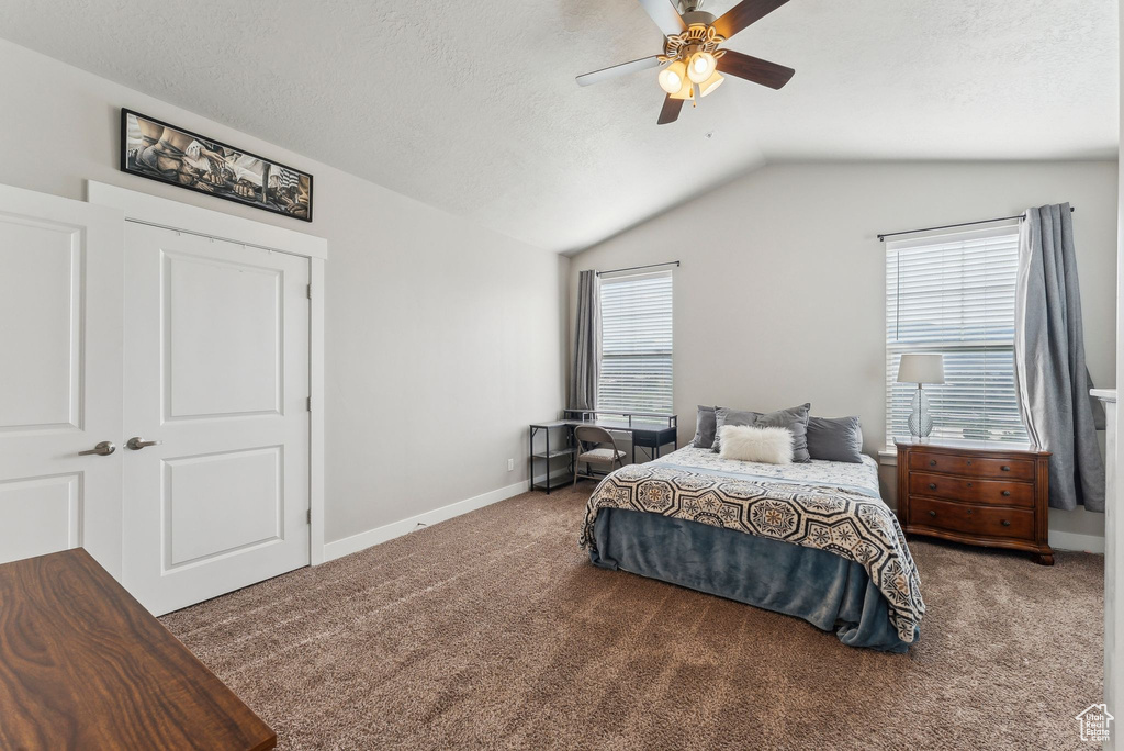 Carpeted bedroom featuring lofted ceiling, baseboards, a textured ceiling, and a ceiling fan