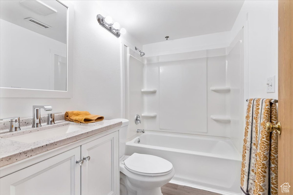 Bathroom with vanity, shower / tub combination, toilet, and wood finished floors