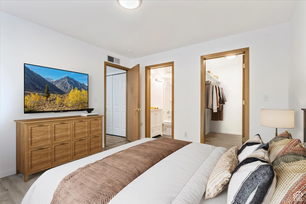 Bedroom featuring a closet, light wood-type flooring, ensuite bathroom, and baseboards