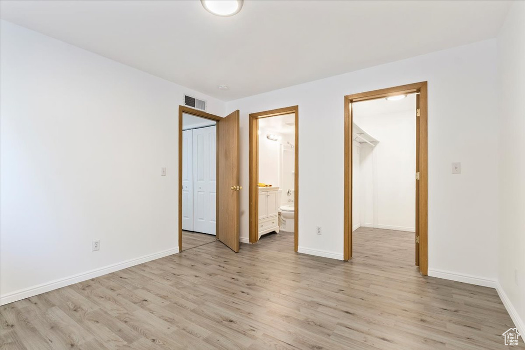 Unfurnished bedroom featuring light wood-type flooring, baseboards, and ensuite bathroom