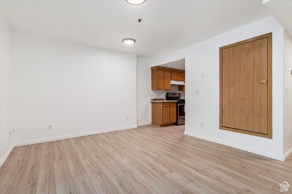 Unfurnished living room featuring light wood finished floors and baseboards