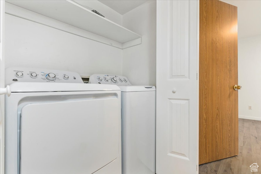 Washroom with washing machine and clothes dryer, light wood finished floors, and baseboards