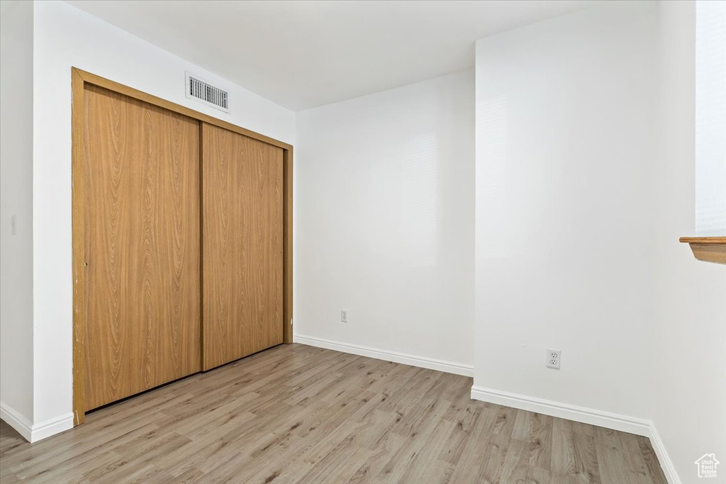 Unfurnished bedroom with light wood finished floors, baseboards, and a closet