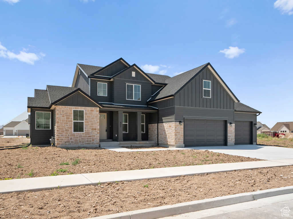 View of front of home with board and batten siding, a porch, a garage, concrete driveway, and roof with shingles