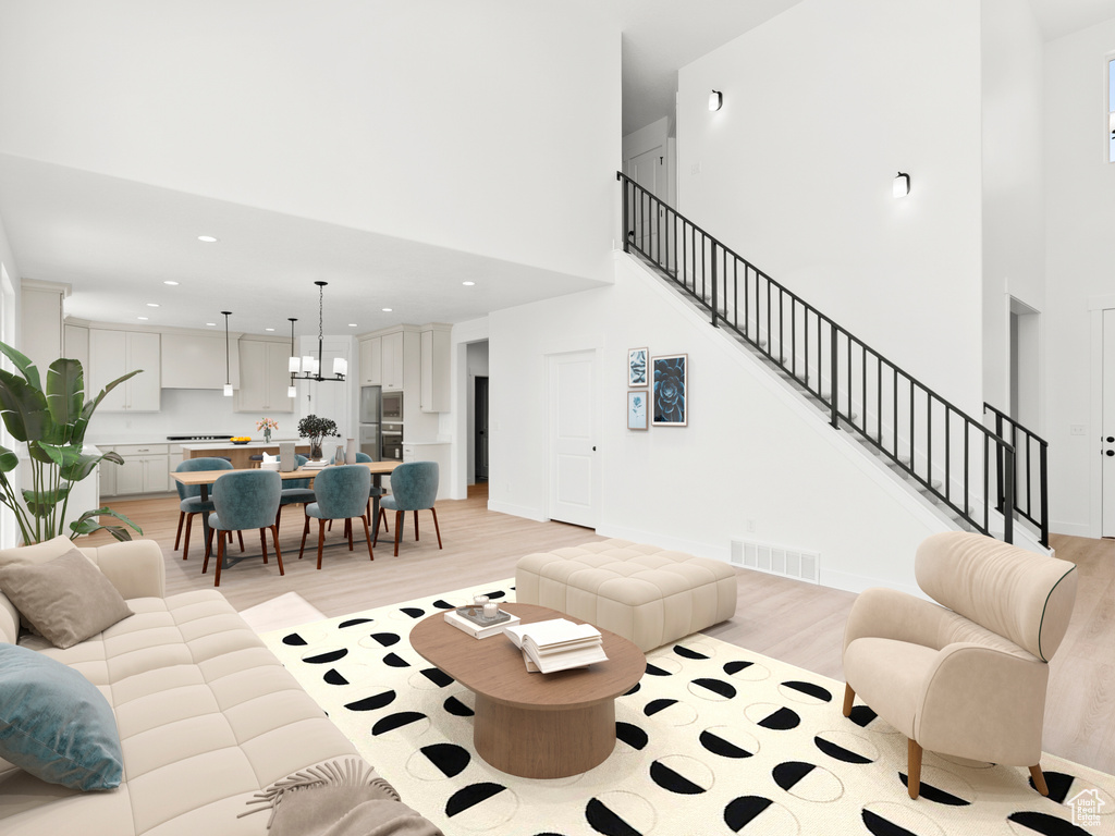 Living room featuring light wood finished floors, a high ceiling, stairway, recessed lighting, and a chandelier