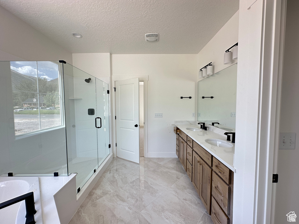 Bathroom with a textured ceiling, double vanity, a stall shower, a bath, and marble finish floors