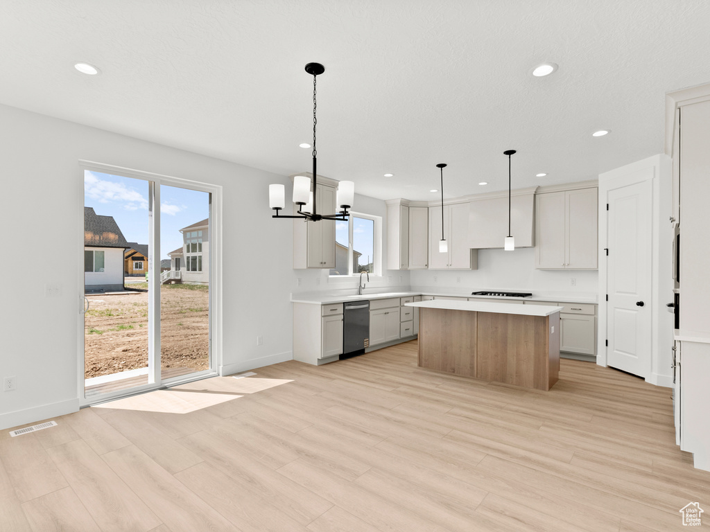 Kitchen featuring stainless steel dishwasher, a kitchen island, light wood-type flooring, and recessed lighting