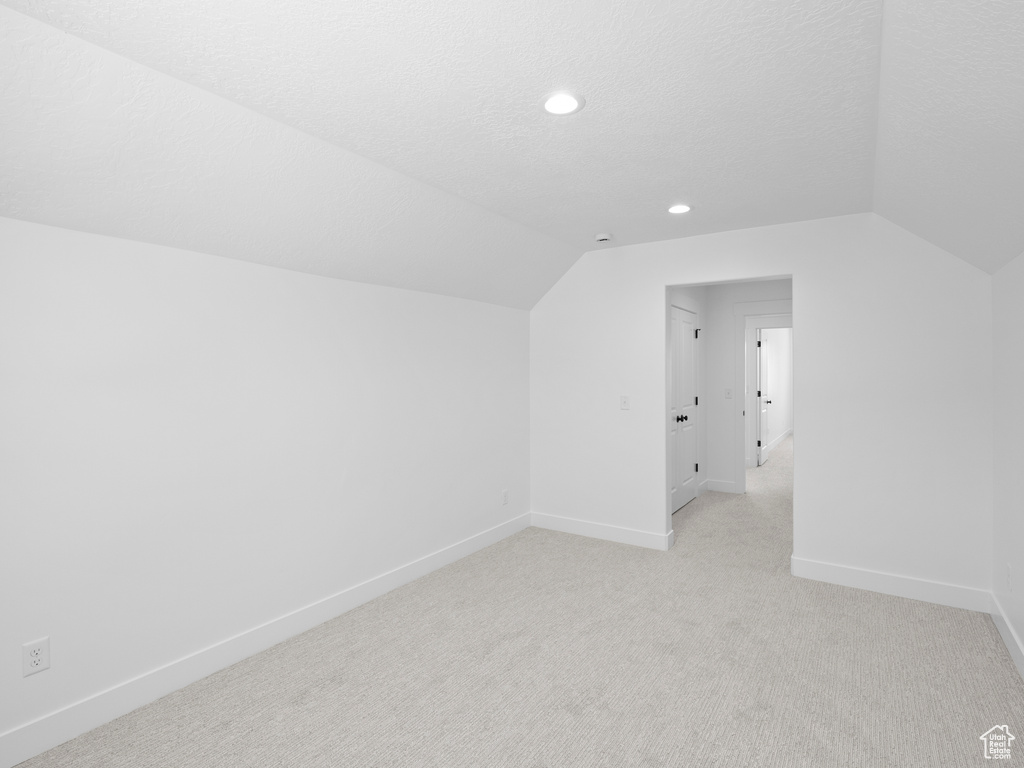 Additional living space featuring vaulted ceiling, light carpet, and recessed lighting