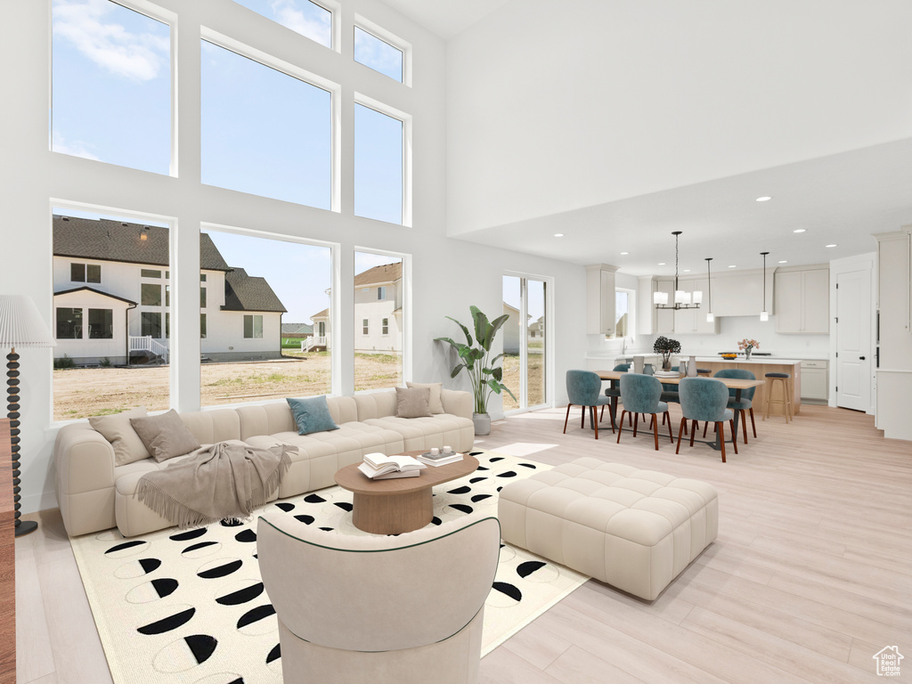 Living room featuring light wood-style flooring, recessed lighting, a chandelier, and a high ceiling