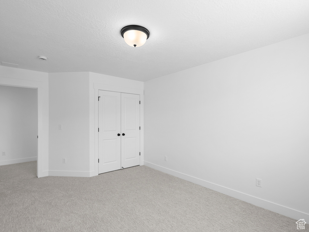 Unfurnished bedroom featuring a closet and light carpet