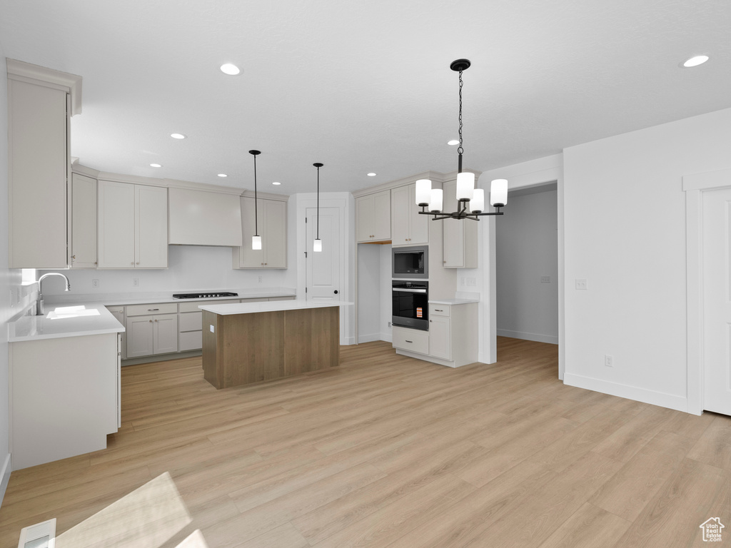 Kitchen featuring stainless steel appliances, a kitchen island, a chandelier, recessed lighting, and light wood-type flooring