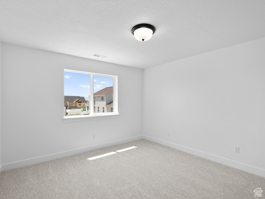 Carpeted empty room featuring baseboards and a textured ceiling