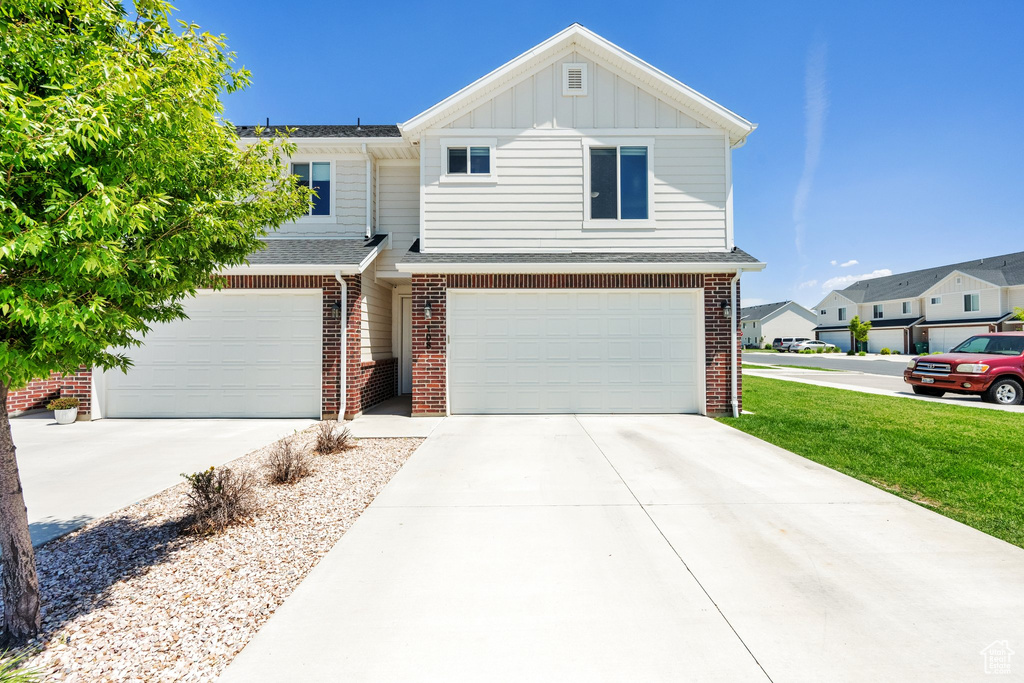 View of front of property featuring concrete driveway, board and batten siding, an attached garage, and brick siding