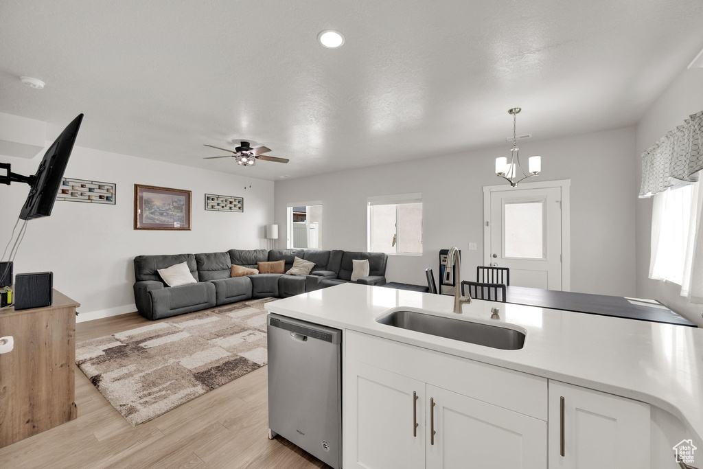 Kitchen featuring dishwasher, a sink, white cabinetry, light countertops, and recessed lighting