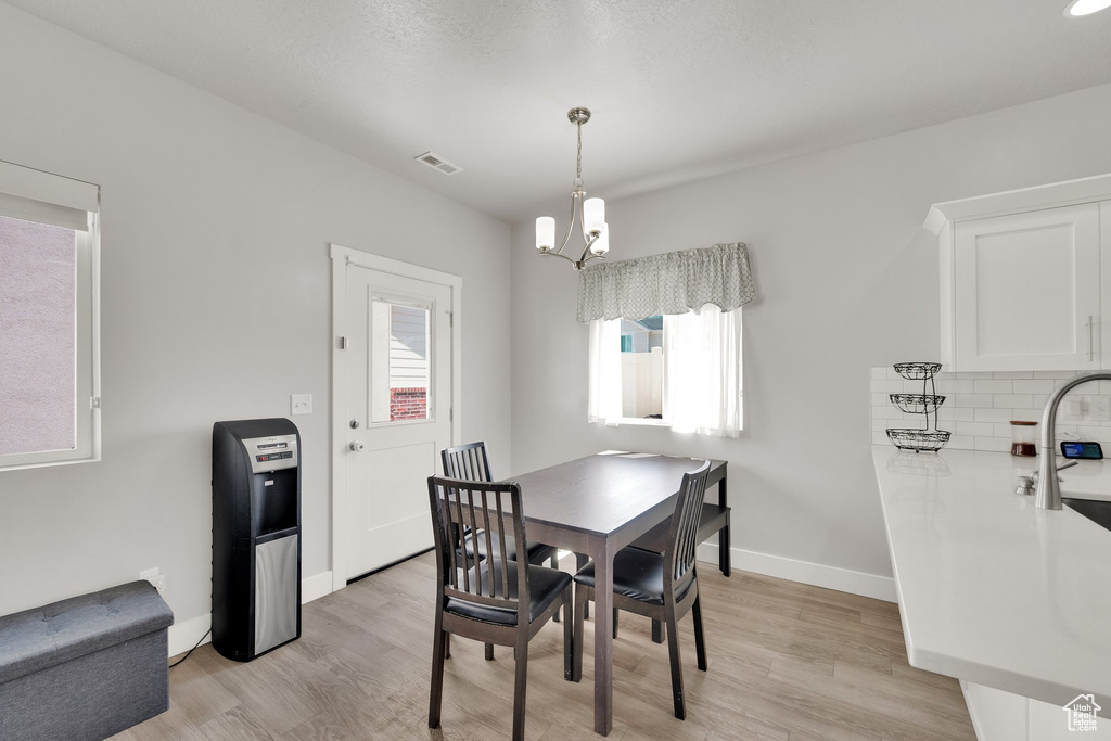 Dining room with light wood-style floors, a chandelier, and baseboards