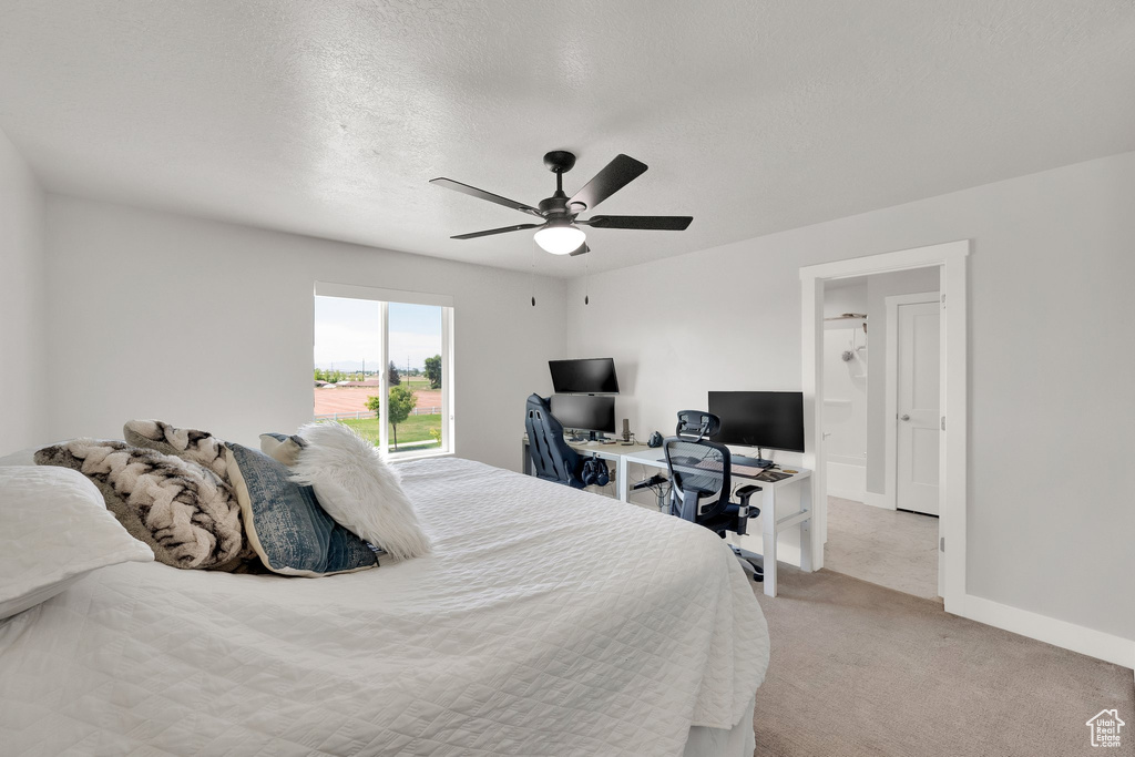 Bedroom featuring light carpet, an office area, baseboards, a textured ceiling, and ceiling fan