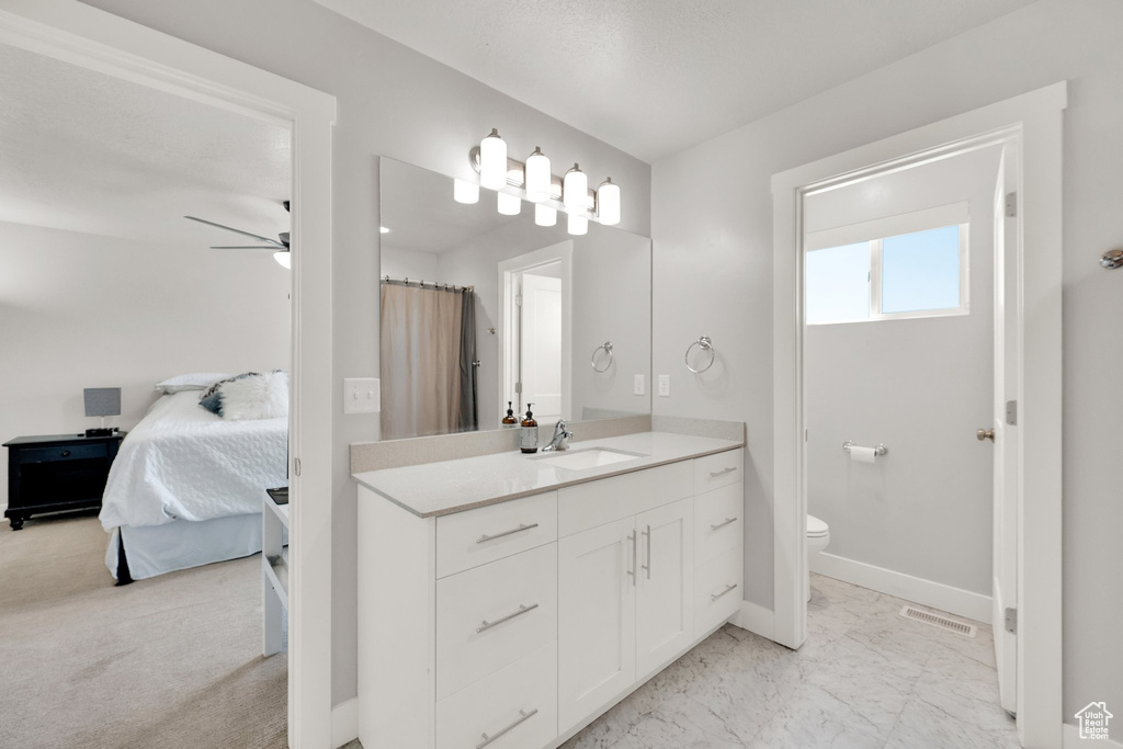 Bathroom featuring toilet, vanity, ensuite bathroom, baseboards, and a ceiling fan