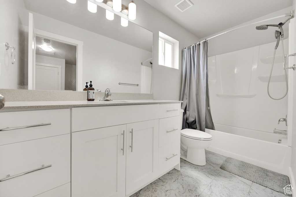 Full bath with vanity, toilet, shower / bath combo with shower curtain, and marble look tiles