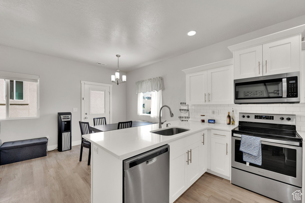 Kitchen featuring appliances with stainless steel finishes, a sink, healthy amount of natural light, light countertops, and recessed lighting