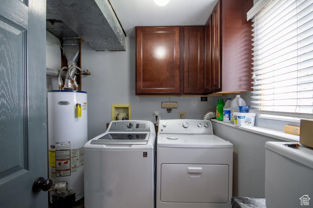 Washroom featuring water heater, separate washer and dryer, and cabinet space