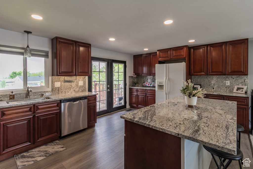 Kitchen featuring white refrigerator with ice dispenser, stainless steel dishwasher, a sink, decorative backsplash, and dark wood finished floors