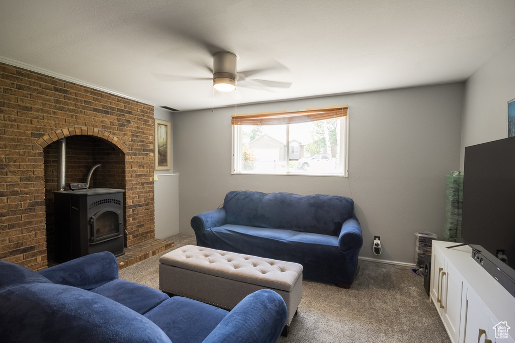 Living room featuring dark colored carpet, ceiling fan, and a wood stove