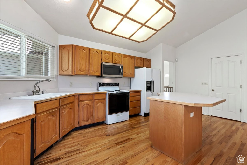 Kitchen featuring range with electric cooktop, stainless steel microwave, white fridge with ice dispenser, vaulted ceiling, and light wood-style floors