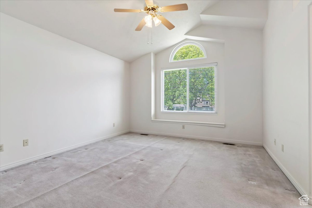 Unfurnished room with carpet, vaulted ceiling, a ceiling fan, and baseboards