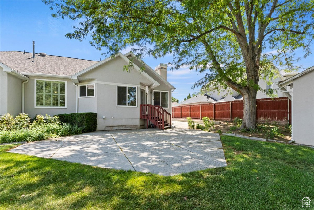 Back of property with a chimney, a patio area, and stucco siding