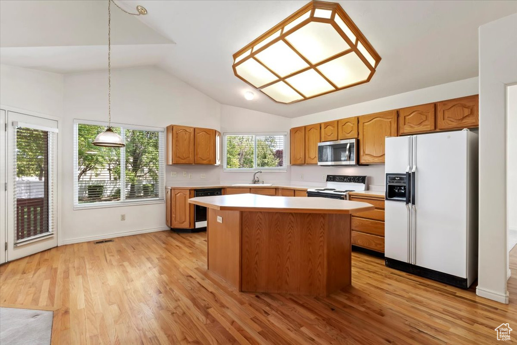 Kitchen with white appliances, a sink, light countertops, a center island, and lofted ceiling