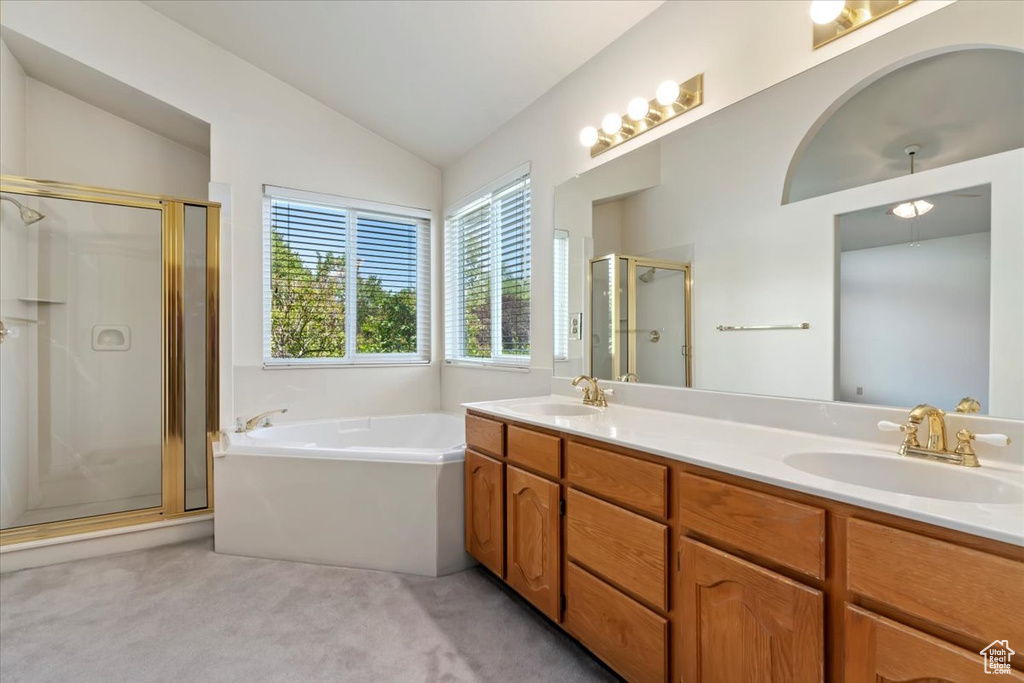 Full bath with a shower stall, lofted ceiling, a garden tub, and double vanity